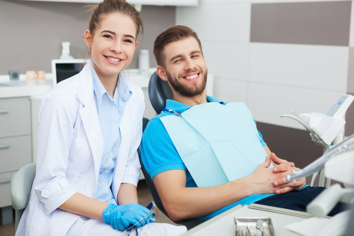 Dentist and patient reviewing dental records in modern dental office treatment room.