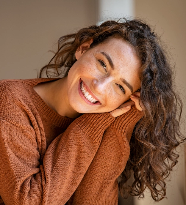 Woman smiling while resting her hand near her face