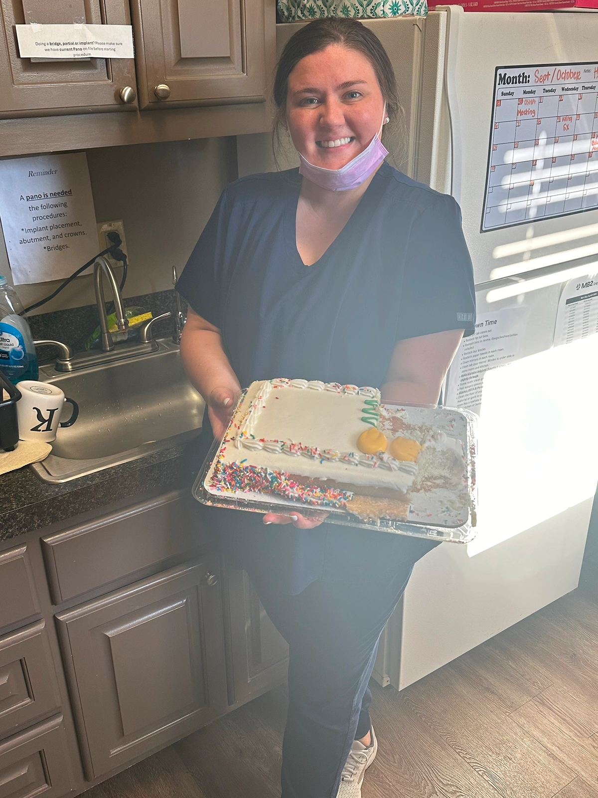 A staff member holding a decorated cake in an office