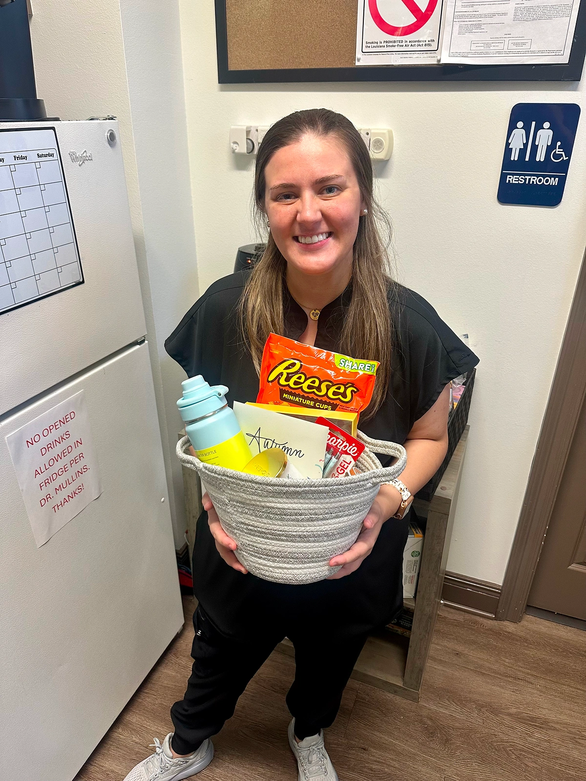 A staff member holding a gift basket and smiling