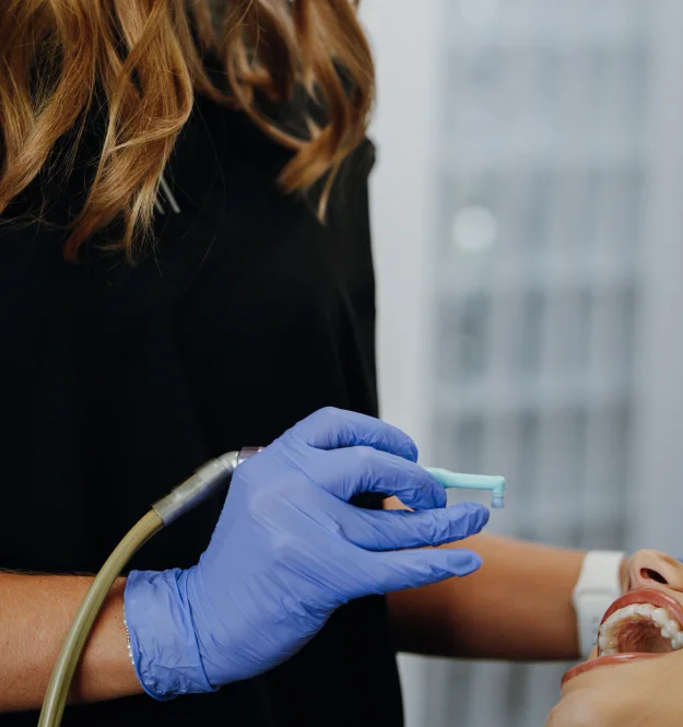A dental professional applying sealant to a patient’s tooth using dental instruments