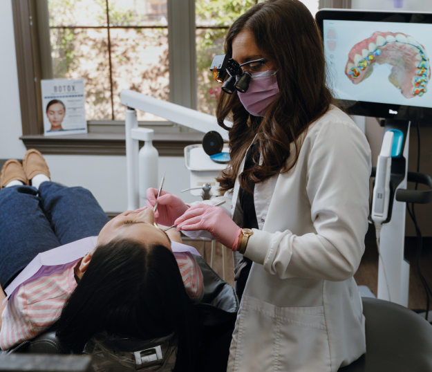  A dentist treating a patient in a dental chair using dental instruments to apply tooth-colored fillings